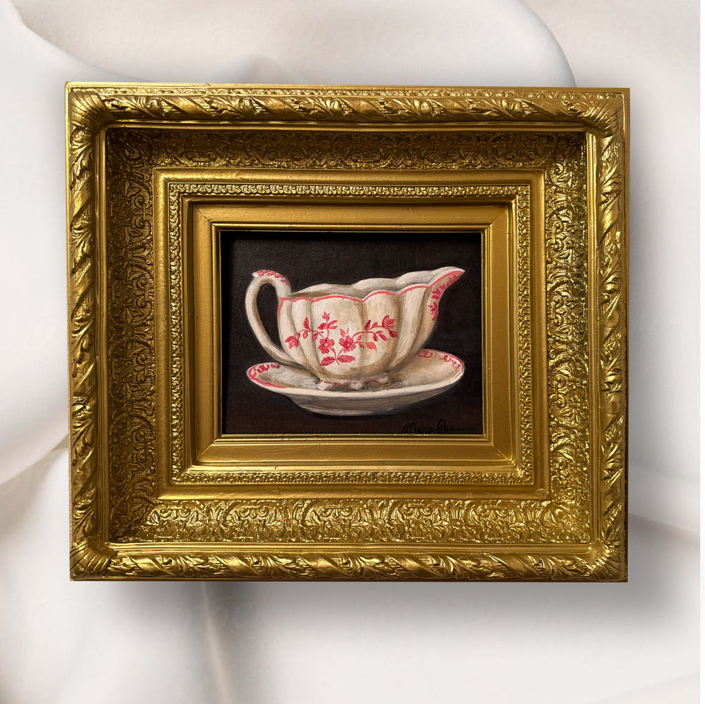 Decorative gold frame with a painting of a teacup and saucer on a white background