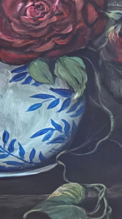 Close-up of a vase with blue floral patterns and red flowers on a dark background