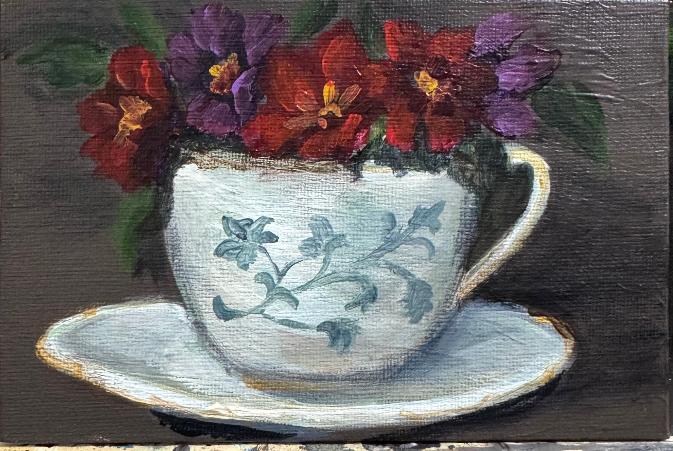 Painting of a teacup with floral design and flowers on a dark background